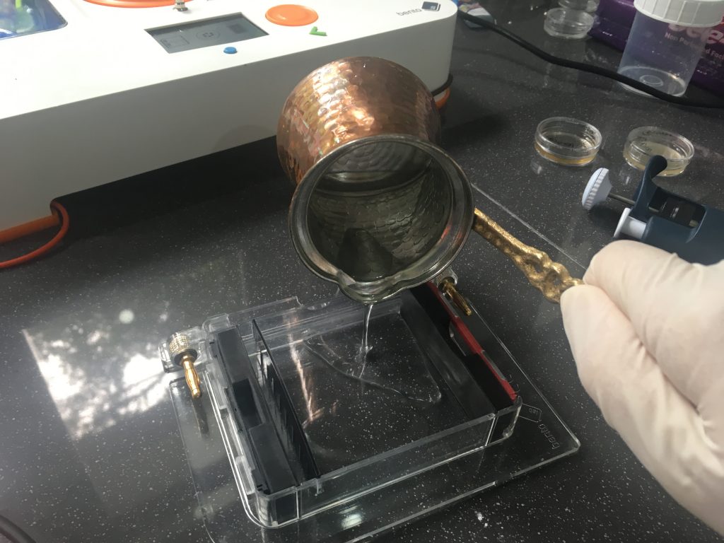 Molten agarose being poured into a Bento Lab gel unit from a traditional Turkish coffee pot.